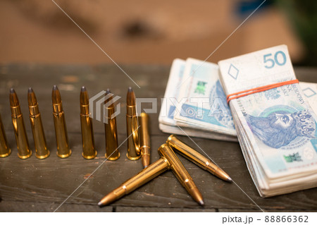 Paper banknotes and rifle cartridges lie on a crate. Paper banknotes and rifle cartridges lie on a crate. 88866362