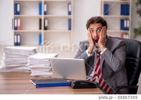 Young male employee unhappy with excessive work in the office Young male employee unhappy with excessive work in the office 88867309