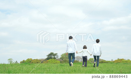 手を繋いで草原を歩く親子　ファミリー　子育て　自然環境 88869443