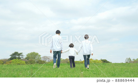 手を繋いで草原を歩く親子　ファミリー　子育て　自然環境 88869444