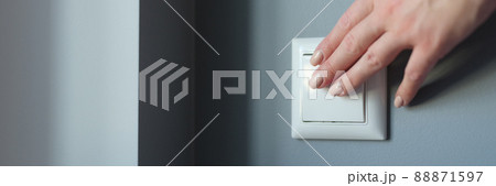 Female hand pressing light switch in apartment closeup 88871597