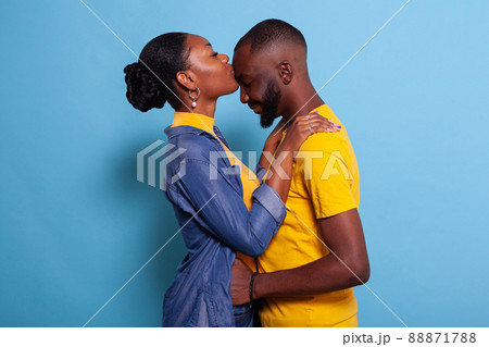 Girlfriend giving partner a kiss on forehead to express love in front of camera. People in relationship showing affection and passion with embrace and kissing. Romantic couple with happy emotions. 88871788