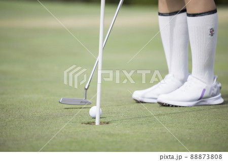 グリーンパッティングイメージ 若い女性足元 転がるゴルフボール グリーンパッティングイメージ 若い女性足元 転がるゴルフボール 88873808