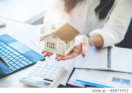 Accountant, businessman, real estate agent, Asian business woman handing model house to customers along with house interest calculation documents for customers to sign 88874452
