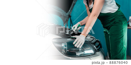 Auto work shop banner. A female mechanic in a green coveralls repairs the engine. Mock up with copy space. The concept of women's equality and service in an auto repair shop Auto work shop banner. A female mechanic in a green coveralls repairs the engine. Mock up with copy space. The concept of women's equality and service in an auto repair shop 88876040