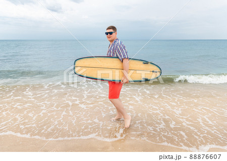 Portrait of young adult stylish caucasian man wear casual shirt and sunglasses enjoy having leisure time surfing at ocean seaside travel vacation tropical resort. Male surfer person surfboard coast Portrait of young adult stylish caucasian man wear casual shirt and sunglasses enjoy having leisure time surfing at ocean seaside travel vacation tropical resort. Male surfer person surfboard coast 88876607