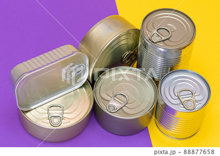 A Group of Stacked Tin Cans with Blank Edges on Split Yellow and Violet Background 88877658