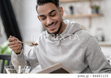 A young man having breakfast and reading a newspaper 88881129