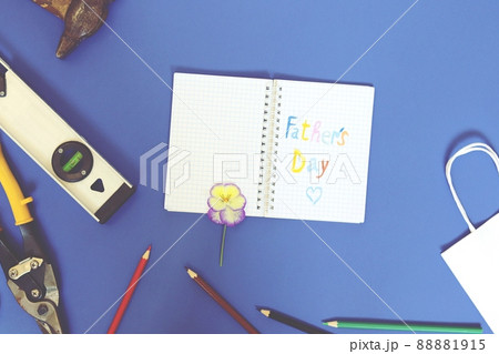 Vintage metal tools, Congratulations on Father's Day in a notebook, flower, pencils, on a blue background, top view, flatly, copy space Vintage metal tools, Congratulations on Father's Day in a notebook, flower, pencils, on a blue background, top view, flatly, copy space 88881915