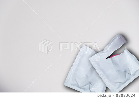 Safe sex and reproductive health concept. Pink opened condom and condom in pack on a white background. 88883624