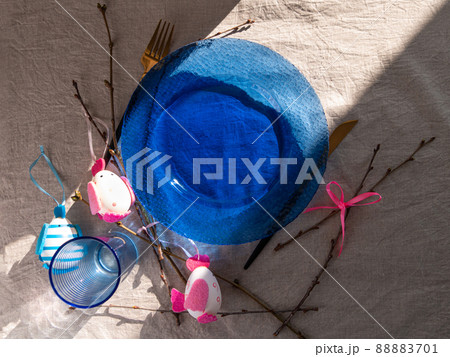 Easter table setting empty blue glass plate cutlery tree branches linen cloth flat lay harsh shadow Festive dish place Easter table setting empty blue glass plate cutlery tree branches linen cloth flat lay harsh shadow Festive dish place 88883701