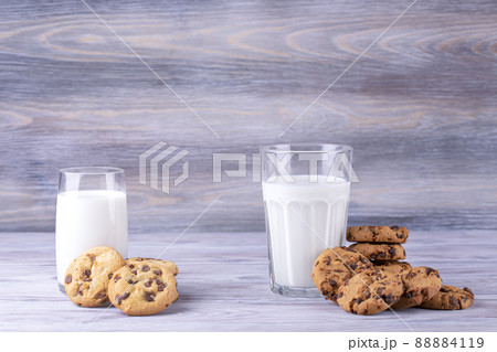 A stack of chocolate chip cookies lies near a glass of milk. Calcium-rich milk. 88884119