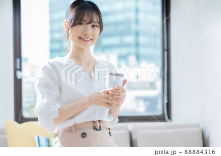 オフィスでタンブラーを手に持って立つ若い女性 88884316
