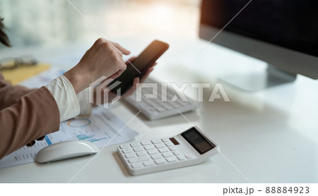 Close up business woman or accountant using mobile phone and working computer at office Close up business woman or accountant using mobile phone and working computer at office 88884923