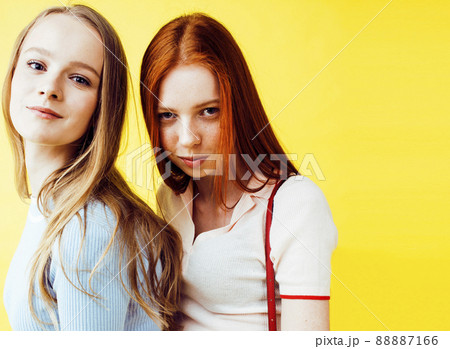 lifestyle people concept: two pretty young school teenage girls having fun happy smiling on yellow background closeup lifestyle people concept: two pretty young school teenage girls having fun happy smiling on yellow background closeup 88887166