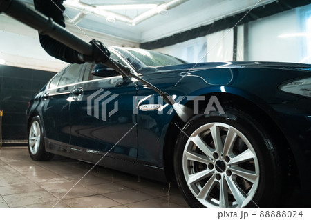 Professional car wash. Detailing employee washes car with pressure washer Professional car wash. Detailing employee washes car with pressure washer 88888024