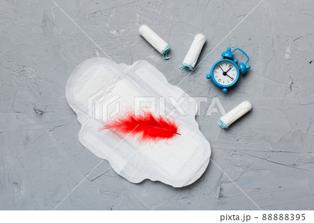 Ringing alarm clock with sanitary female tampons and menstrual sanitary pads. Medical concept of woman critical days and menstruation. Female daily hygiene. Copy space Ringing alarm clock with sanitary female tampons and menstrual sanitary pads. Medical concept of woman critical days and menstruation. Female daily hygiene. Copy space 88888395