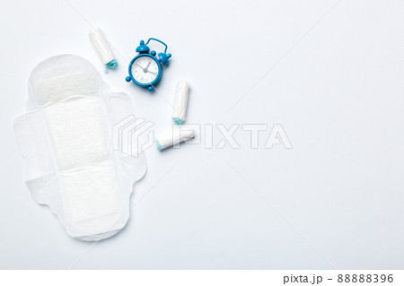 Ringing alarm clock with sanitary female tampons and menstrual sanitary pads. Medical concept of woman critical days and menstruation. Female daily hygiene. Copy space 88888396