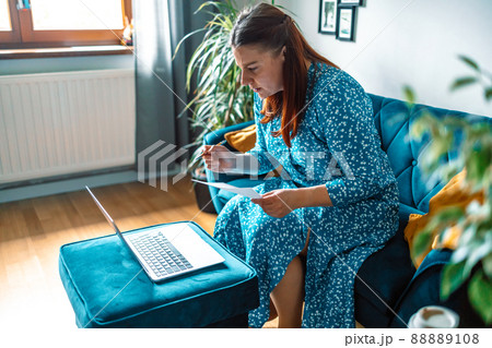 beautiful serious woman using laptop paying bills online and managing home budget 88889108