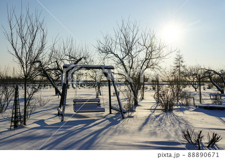 snowy wooden swing bench in the snow covered garden in the winter sunlight 88890671