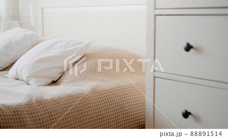 The interior of the room in beige tones with a bed and pillow, closet and flowers on it 88891514
