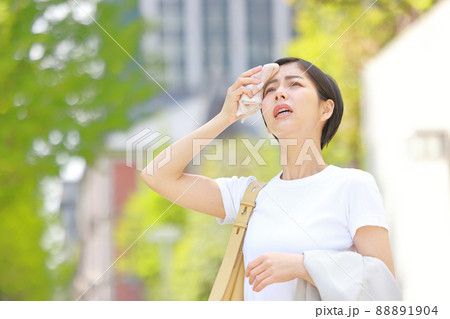 額の汗をハンカチで拭き陽射しを気にする女性1 88891904