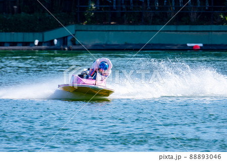 水しぶきを上げながらコーナーを曲がるボートレースの選手 88893046