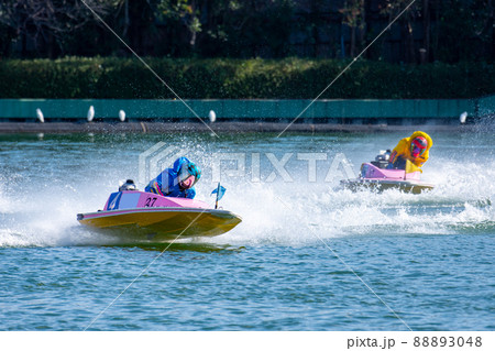 水しぶきを上げながらコーナーを曲がるボートレースの選手 88893048
