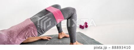 Fitness resistance band glute bridge with hip abduction exercise woman workout at home. Fit girl training with circle hoop booty bands for glute strengthening banner panorama 88893410