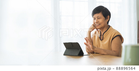 Asian Mature woman using digital tablet computer at home 88896564