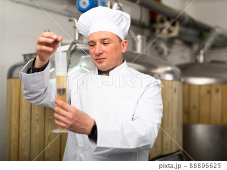 Man brewmaster measuring beer with alcoholometer Man brewmaster measuring beer with alcoholometer 88896625