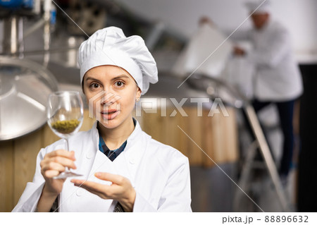Successful female brewmaster showing hop pellets in glass Successful female brewmaster showing hop pellets in glass 88896632