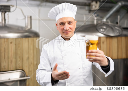 Portrait of brewer who is standing with glass of beer on his workplace in brew-house Portrait of brewer who is standing with glass of beer on his workplace in brew-house 88896686