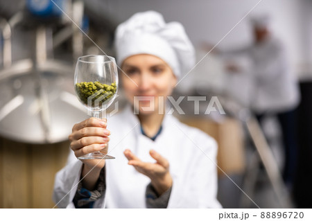 Female brewer showing natural granulated hops in glass 88896720