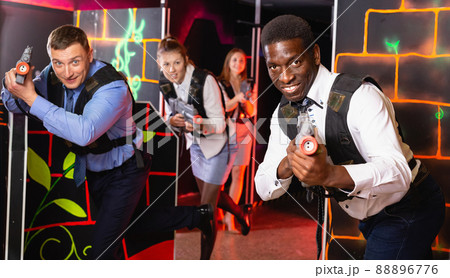 Group of colleagues holding laser pistols playing laser tag game 88896776