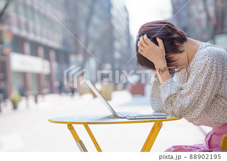カフェで頭を抱えて悩む女性 88902195