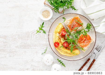 Omelette or omelet, fresh arugula and tomato salad and toasts with butter and salted salmon, top view Omelette or omelet, fresh arugula and tomato salad and toasts with butter and salted salmon, top view 88903863