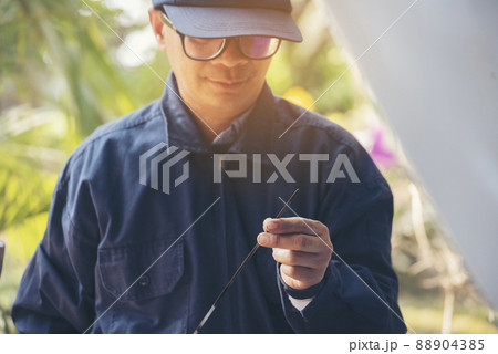 Car Mechanic man hand checking dipstick engine oil car mechanical on site service. Close up hand man check engine oil level Locate dipstick, wipe clean, check dipstick level before fill up engine oil 88904385