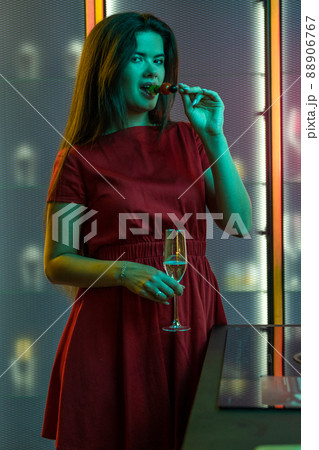 Young brunette celebrating with champagne and snacks alone in home kitchen 88906767