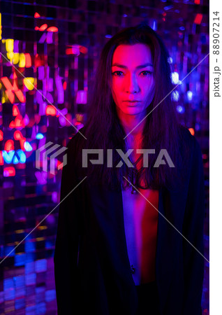 Close-up portrait of an androgenic model. Male transgender in studio with neon light. 88907214