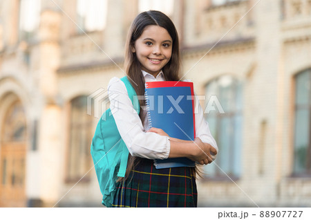 Little girl student school uniform and backpack hold books, formal education concept Little girl student school uniform and backpack hold books, formal education concept 88907727