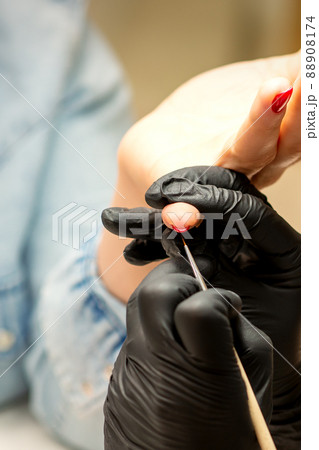 Professional manicure. A manicurist is painting the female nails of a client with red nail polish in a beauty salon, close up. Beauty industry concept 88908174