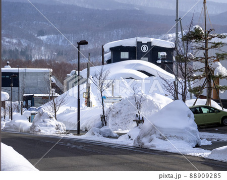 厚く雪の積もった建物と道端の雪塊 (北海道、俱知安、ひらふ坂) 88909285