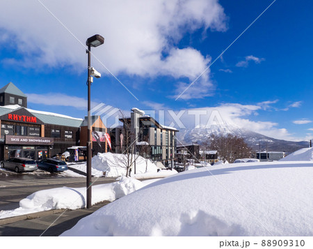 スキー場山麓に並ぶ用品店と雲のかかった羊蹄山 (北海道、俱知安、ひらふ坂) 88909310