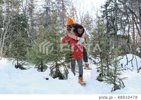 Cheerful young Black man in love giving his girlfriend piggyback ride while hiking in mountains on winter day Cheerful young Black man in love giving his girlfriend piggyback ride while hiking in mountains on winter day 88910478
