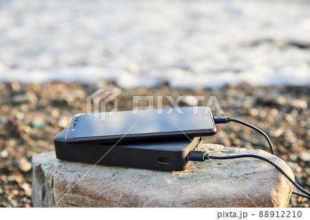 Powerbank charges the phone on the beach by the sea Powerbank charges the phone on the beach by the sea 88912210
