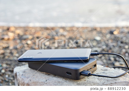 Powerbank charges the phone on the beach by the sea 88912230