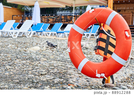Lifebuoy on a pebble beach against the background of sun loungers 88912288