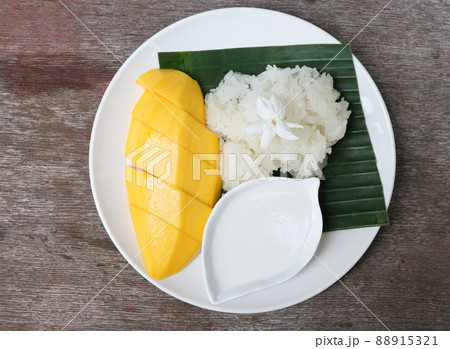 Sweet mango with sticky rice in the white plate topping with Jasmine flower, cuisine of Asia for summer Sweet mango with sticky rice in the white plate topping with Jasmine flower, cuisine of Asia for summer 88915321
