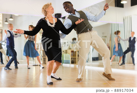 Woman pensioner with african man practising charleston Woman pensioner with african man practising charleston 88917034